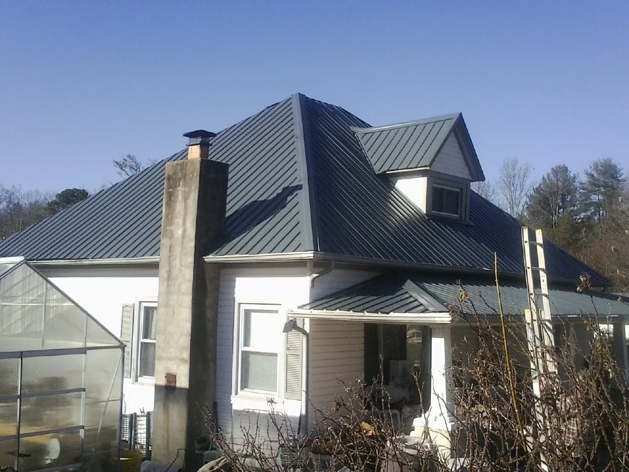 Dark blue standing seam metal roof on a white farmhouse with dormer — Slate & Tile Roof Repair by Roofing Brothers in Dassel