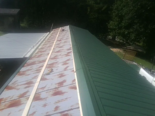 Old rusted panels beside newly installed green metal roofing — Wind Damage Roof Repair by Roofing Brothers in Dassel