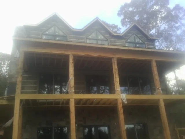 Dormers and porch framing on a large log home under construction — Roof Coating work by our crew in Dassel
