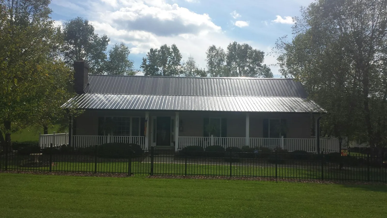 Gray metal roof on a brick ranch with a full width front porch — Gutter Guard Installation work by our crew in Dassel