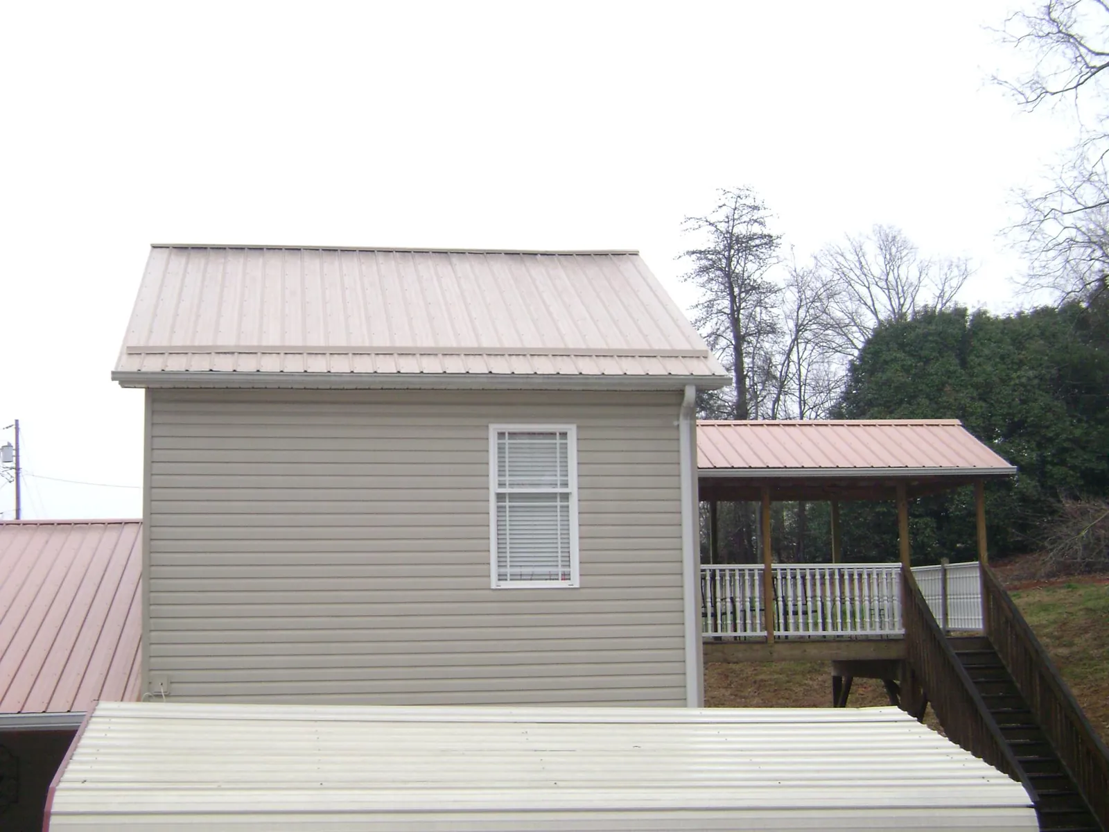 Tan metal roofs on a two story addition and attached porch, from a Roof Replacement job in Dassel