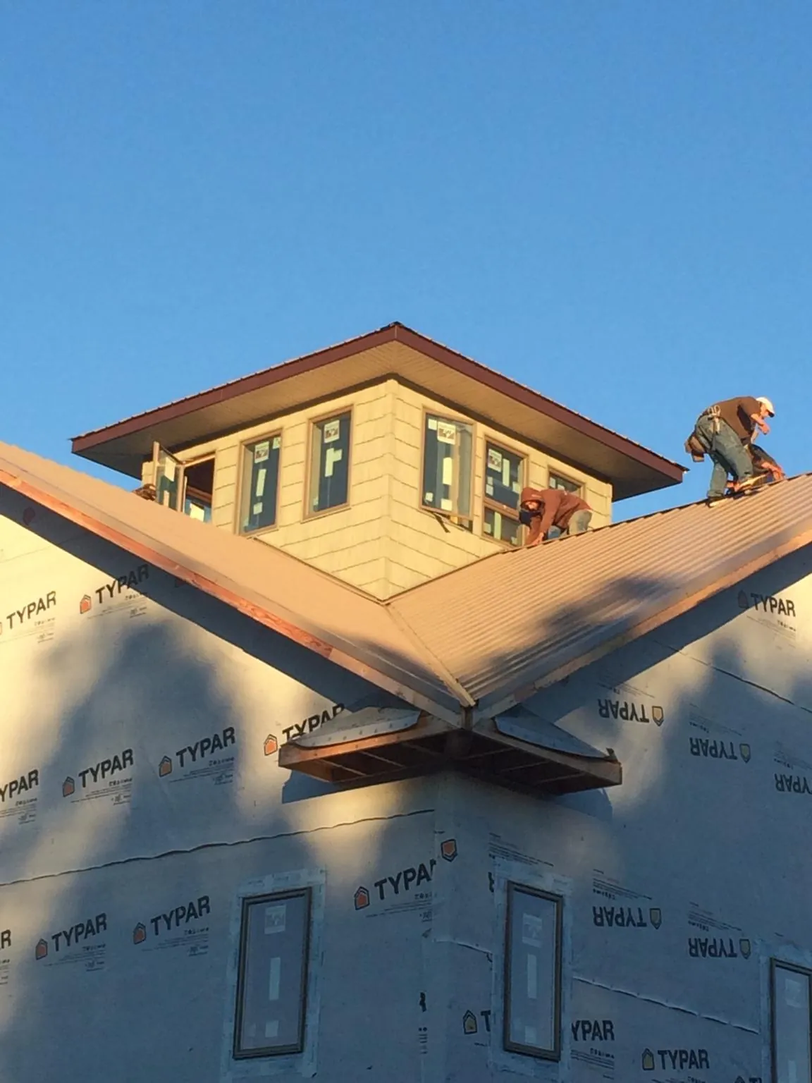Roofers working around a rooftop cupola on a new metal roof at sunset — Roof Waterproofing in Dassel by Roofing Brothers